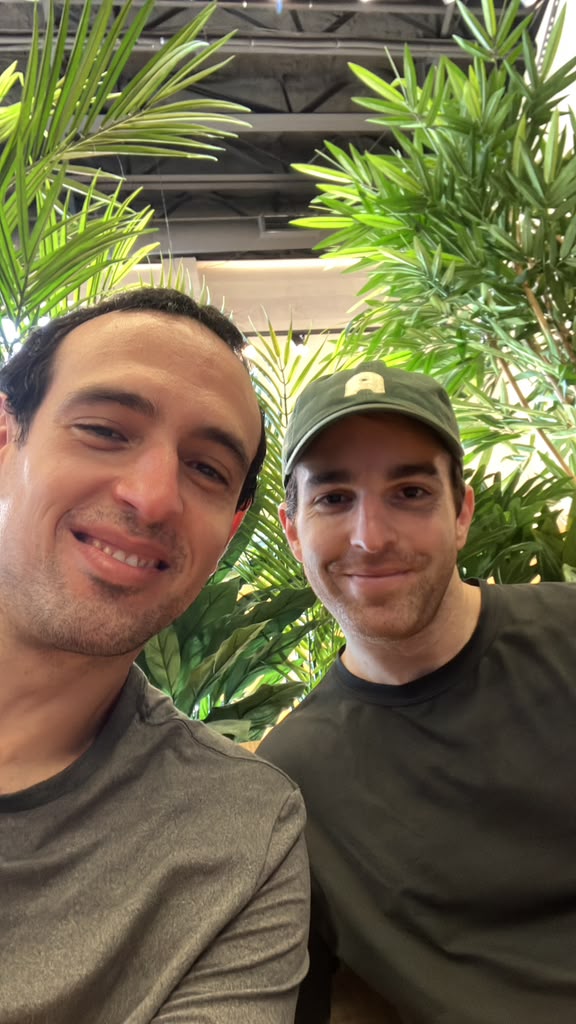Selfie of Paulo with a friend in a green cap among plants
